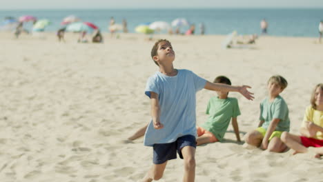 Long-shot-of-boy-running-on-beach-and-kicking-ball-with-leg